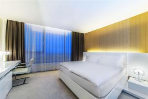 a bedroom with a large white bed and a desk at NH Bratislava Gate One in Bratislava