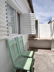 two green chairs sitting on a balcony with a window at Los Olivos Apart in Cafayate