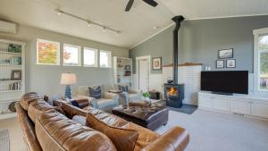 a living room with a leather couch and a fireplace at 3-Home Coastal Retreat w Sauna Firepit Greenhouse Seabright Haven by AvantStay in Coupeville