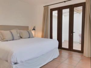 a bedroom with a white bed and sliding glass doors at Casapueblo Rent Cachagua CP 18 in Cachagua