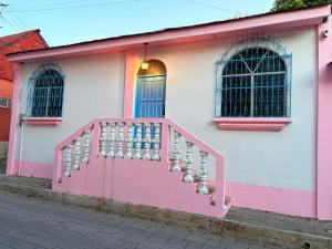 a pink and white building with a pink door and stairs at Casa Azucena in Flores
