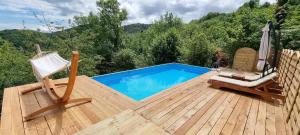 a wooden deck with a swimming pool and two chairs at Chalet Vito - Where Luxury Meets Tranquility in Gregurić Breg