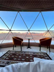a room with two chairs and a bed and a large window at Rum Aranda camp & Jeep Tour in Wadi Rum +66 photos