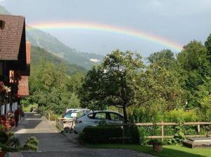 a rainbow in the sky with cars parked in a driveway at Glyssen 22 Schwanden in Kienholz