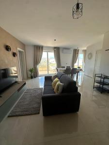 a living room with a black couch and a table at PrimeRose Penthouse in Sannat