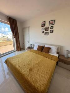 a bedroom with a large bed with a large window at PrimeRose Penthouse in Sannat