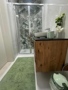 a bathroom with a sink and a shower with a green rug at PrimeRose Penthouse in Sannat