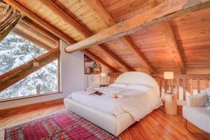 Un dormitorio con una cama grande en una habitación con techos de madera. en Romito Lodge Apartment Mountain Retreat - Happy Rentals, en Cesana Torinese