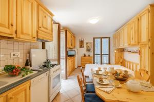 a kitchen with wooden cabinets and a wooden table with a dining room at Relax In Pineta - Happy Rentals in Oulx