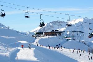 La Casa Di Dadà - Happy Rentals في أولكس: مجموعة من الأشخاص على منحدر للتزلج تحت مصعد التزلج