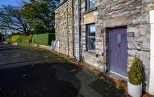 a purple door on the side of a stone building at 1, Bank End Cottages in Ingleton