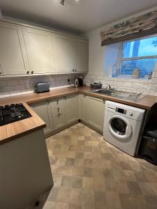 eine Küche mit weißen Schränken und einer Waschmaschine in der Unterkunft 1, Bank End Cottages in Ingleton  + 3 Fotos