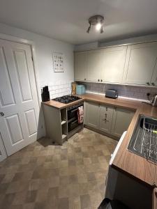 eine Küche mit weißen Schränken und einem Herd mit Backofen in der Unterkunft 1, Bank End Cottages in Ingleton 