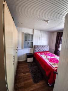 une petite chambre avec un lit avec une couverture rouge dans l'établissement Casa de temporada em Balneário Gaivota- Praia Onda Azul, à Balneário Gaivotas