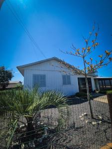 une maison blanche avec un arbre devant dans l'établissement Casa de temporada em Balneário Gaivota- Praia Onda Azul, à Balneário Gaivotas