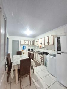 une cuisine avec une table, des chaises et un réfrigérateur dans l'établissement Casa de temporada em Balneário Gaivota- Praia Onda Azul, à Balneário Gaivotas