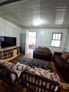 un salon avec un canapé et une télévision à écran plat dans l'établissement Casa de temporada em Balneário Gaivota- Praia Onda Azul, à Balneário Gaivotas