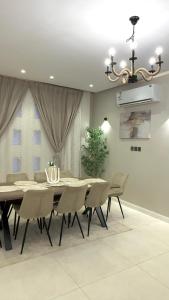 a dining room with a table and chairs and a chandelier at فيلا آنسي Villa Annecy in AlUla