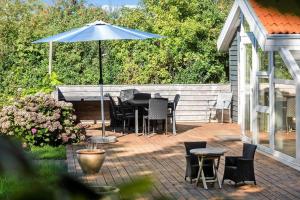 a patio with a table and chairs and an umbrella at N334-Karrebaeksminde-Reedtzholmvej-127 in Enø By
