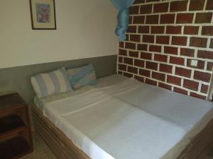 a bed in a room with a brick wall at baobolong guesthouse in Koli Kunda +58 photos