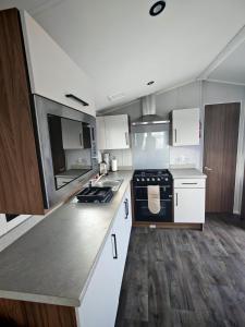 a large kitchen with white cabinets and black appliances at Primrose Valley Primrose field 4 in Filey