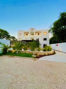 a large white building with palm trees in front of it at Hotel Puerto Tixkokob in Tixkokob +53 photos