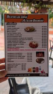 a person holding a sign in front of a menu at Hospedagem Tia Lene Pacoval Soure in Soure
