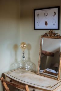 une bouteille en verre sur une table à côté d'un miroir dans l'établissement Hogchester Cottage, à Bridport 17 autres photos
