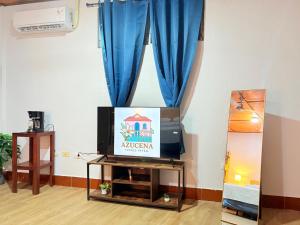 a living room with a tv and a blue curtain at Casa Azucena in Flores