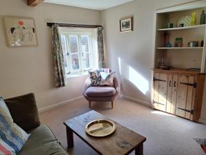 un salon avec un canapé et une table dans l'établissement Hogchester Cottage, à Bridport