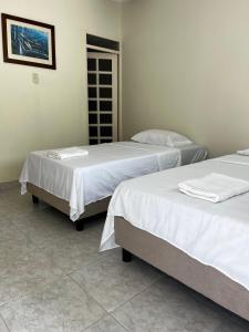 two beds in a room with white sheets at Hotel brisas del opía in Piedras