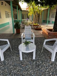 three white chairs and a table with a plant on it at Hotel brisas del opía in Piedras