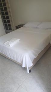 a large white bed with a white blanket on it at Hotel brisas del opía in Piedras