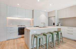 ゴールドコーストにあるMiles at Kirra Point 302のキッチン(白いキャビネット、緑のスツール付きカウンター付)