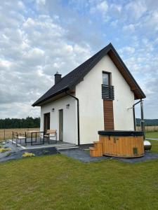 une petite maison blanche avec une table de pique-nique devant elle dans l'établissement Leśny Zakątek Brzezinki, 
