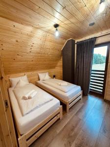 une chambre avec deux lits dans une cabane en bois dans l'établissement Leśny Zakątek Brzezinki, 