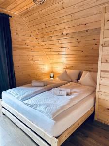 - un lit dans une chambre en bois avec 2 serviettes dans l'établissement Leśny Zakątek Brzezinki,  6 autres photos