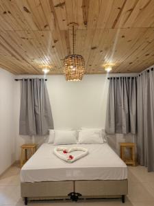 a bedroom with a white bed with a wooden ceiling at Chalé vista mar in São Miguel do Gostoso