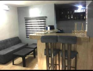 a kitchen with a bar with stools and a couch at Rosecourt Hotel & Suites in Enugu