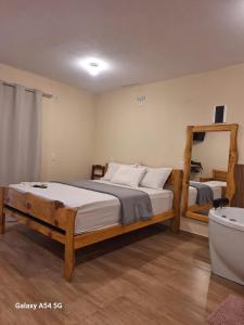 a bedroom with a bed and a tub and a mirror at Chalé Aconchego in Camanducaia