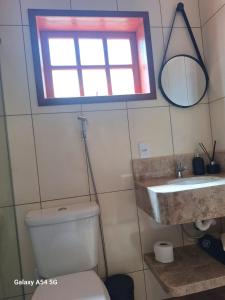 a bathroom with a toilet and a sink and a window at Chalé Aconchego in Camanducaia +7 photos
