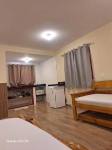 a room with two beds and a kitchen with a refrigerator at Chalé Aconchego in Camanducaia