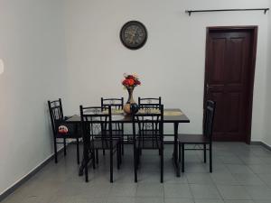 a dining room with a table and chairs and a clock at Appartement Brel in Yaoundé
