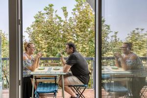 Un hombre y dos mujeres sentados a una mesa frente a una ventana en Un séjour a empuriabrava-TERRASSE-VUE MER -CLIME- WIFI PARKING, en Empuriabrava 48 fotos más