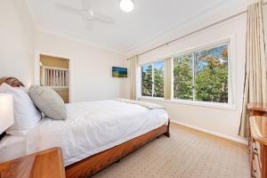 a white bedroom with a bed and a window at Luxury 3 bedroom 2 bathroom full home with easy access near Cronulla in Lilli Pilli