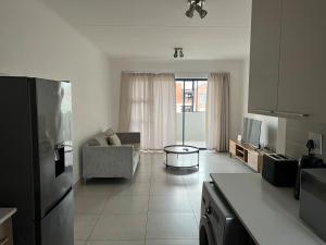 a kitchen with a refrigerator and a living room at Spacious 2 bedroom, 2 bathroom unit in Pretoria