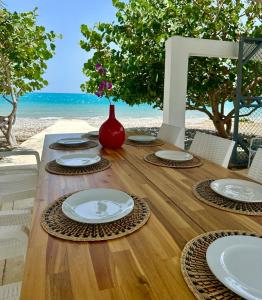 una mesa de madera con platos y un jarrón rojo encima en Front Beach Villa, Pool & Basket, 