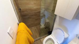een badkamer met een douche en een toilet met een gele handdoek bij 06 Loft Espectacular - Aire Acondicionado, Consulado in Guadalajara