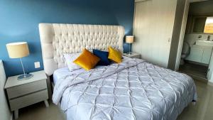 een slaapkamer met een groot bed met gele en blauwe kussens bij 06 Loft Espectacular - Aire Acondicionado, Consulado in Guadalajara