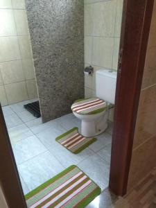 a bathroom with a toilet and two mats on the floor at Pousadinha Mangabeiras II in São Mateus